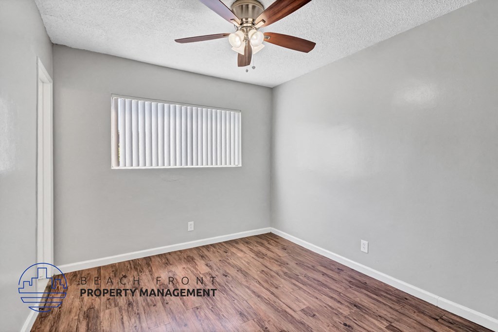 A room with a ceiling fan and wooden flooring.